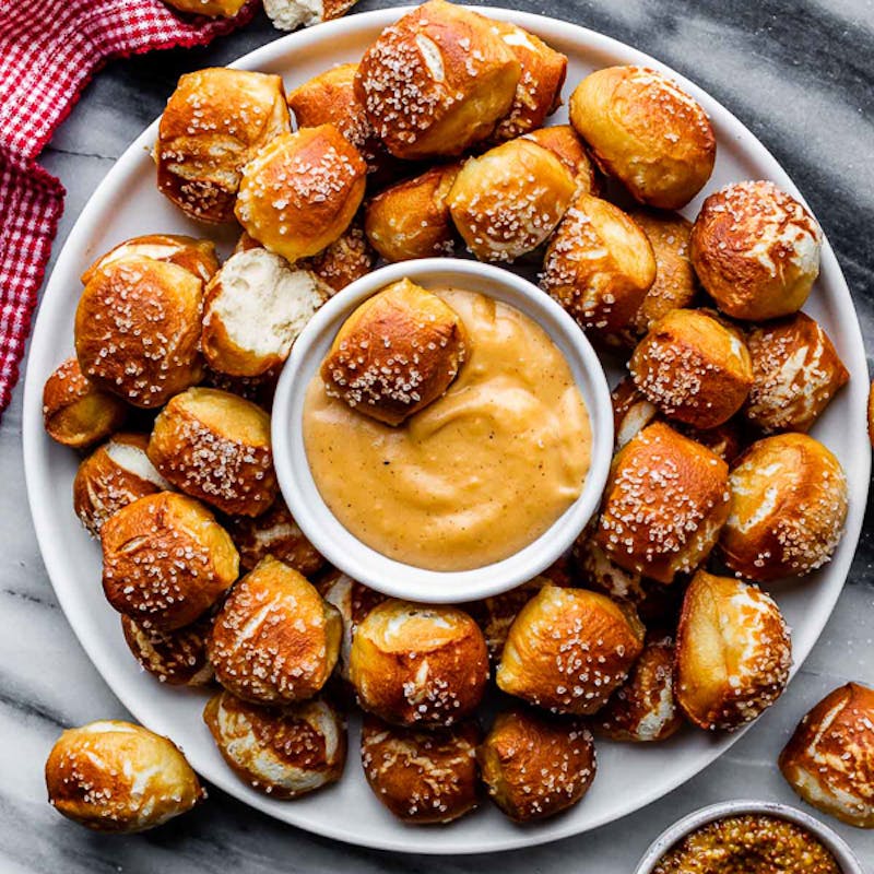 pretzel bites on white plate with cheese sauce
