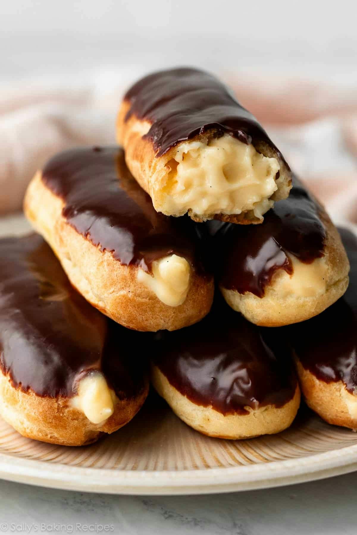 eclairs with pastry cream inside and chocolate ganache on top in a stack