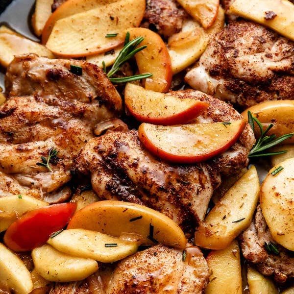 chicken with apple slices in a cast iron skillet