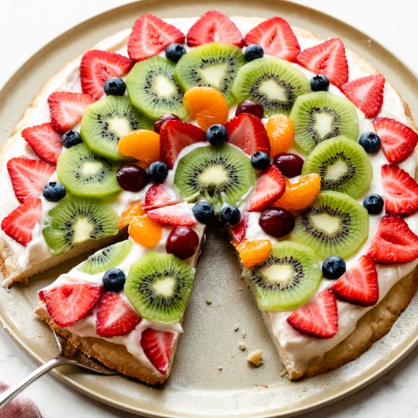 Photo of fruit pizza with a slice cut