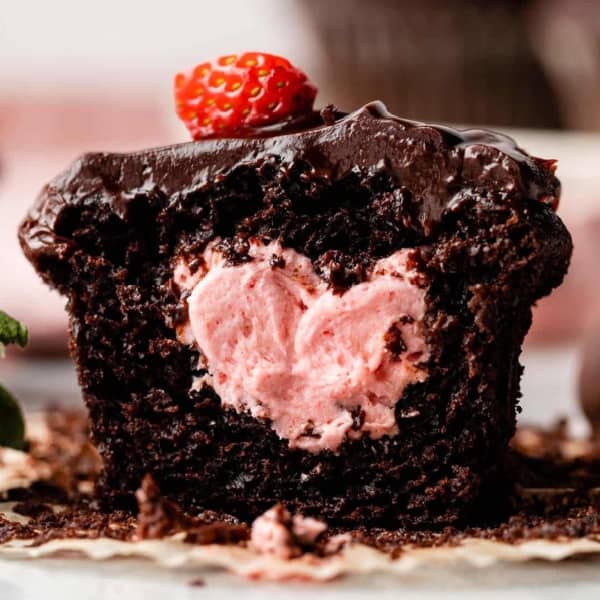 Chocolate cupcake cut in half, showing strawberry buttercream filling. 