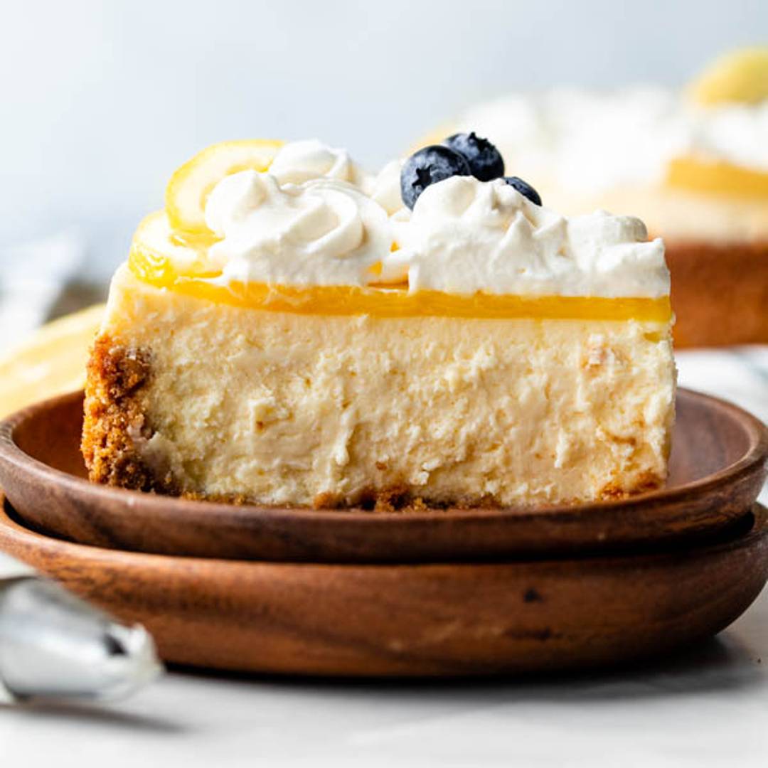slice of lemon cheesecake with whipped cream and blueberries on top