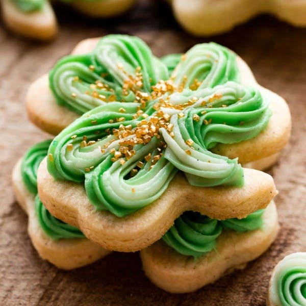 shamrock shaped sugar cookies decorated with green buttercream and gold sprinkles