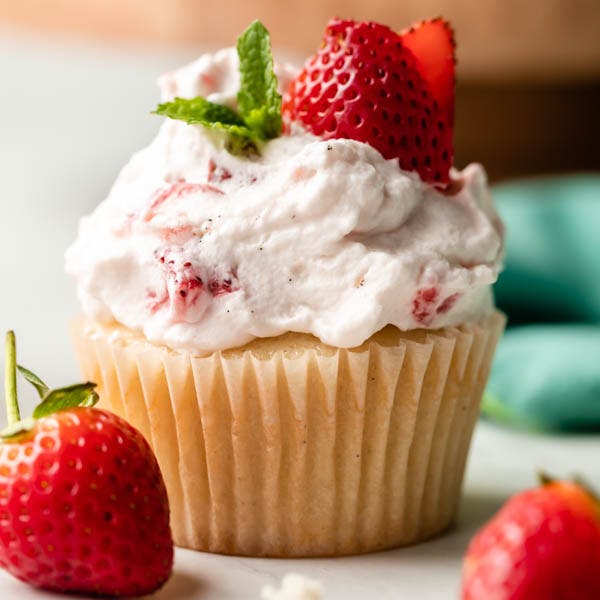 vanilla cupcake with strawberry whipped topping and fresh strawberries on top