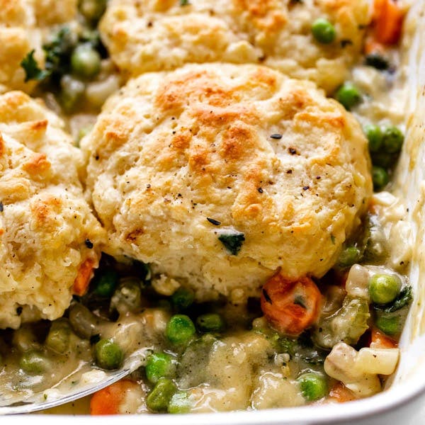 vegetable pot pie in a casserole dish with golden biscuits on top