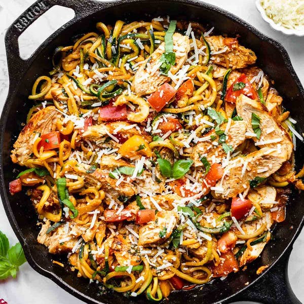 bruschetta chicken with zucchini noodles in a cast iron skillet