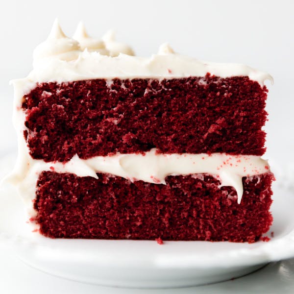 Slice of two layer red velvet cake with cream cheese frosting