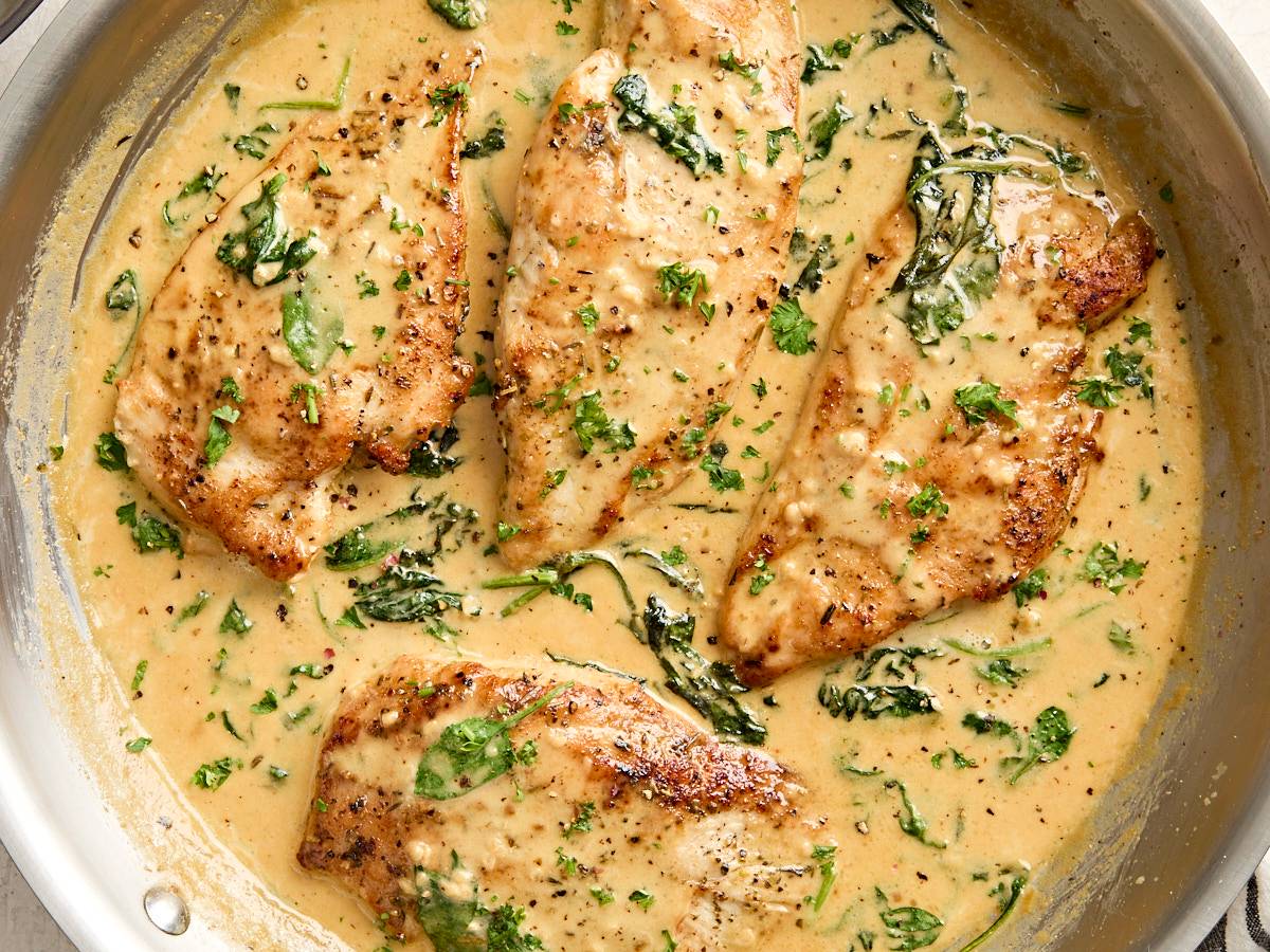 Overhead view of a platter of buffalo wings with ranch sauce in the middle and celery sticks around the sides.