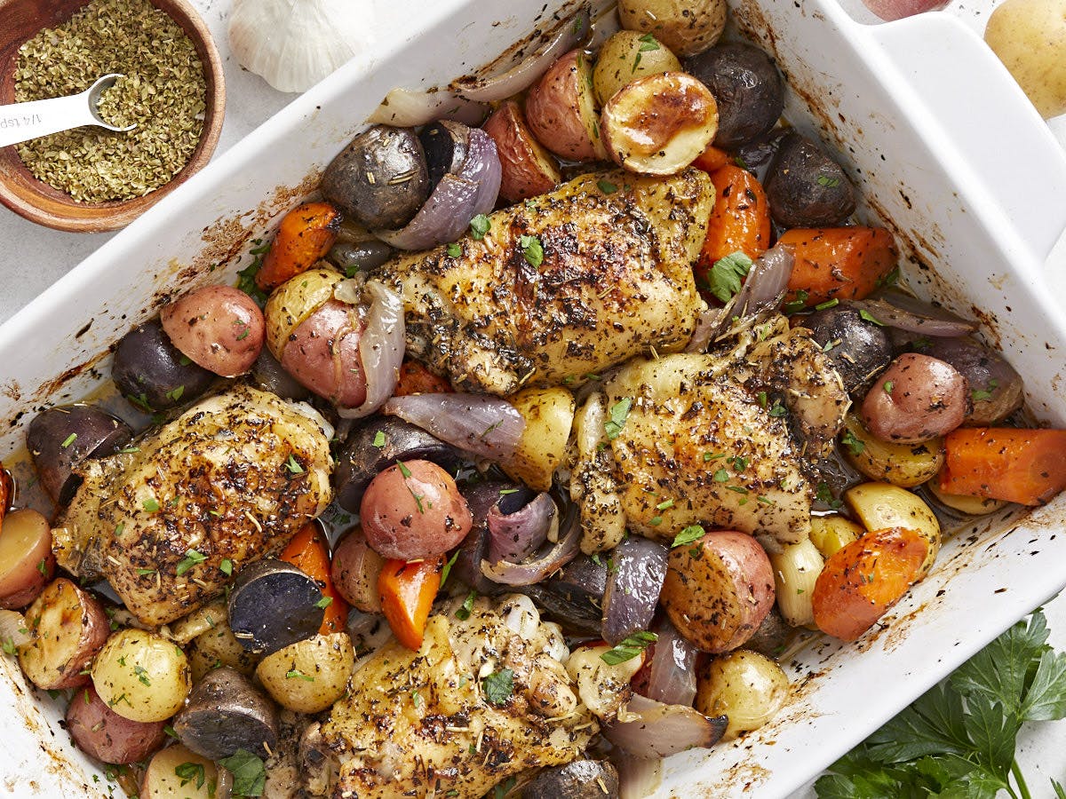 Overhead view of roasted chicken and vegetables in a deep casserole dish.