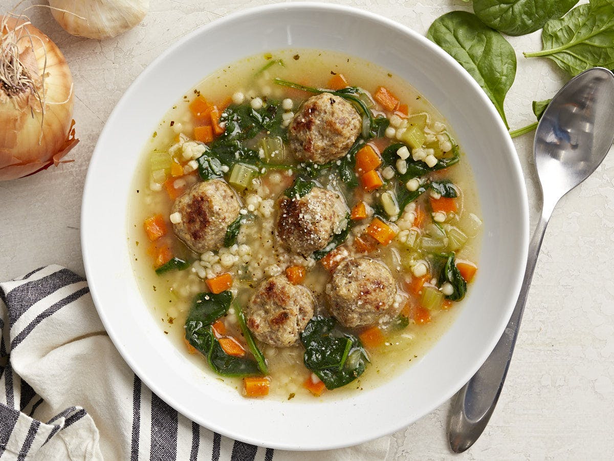 Overhead view of Italian wedding soup in a white serving bowl.