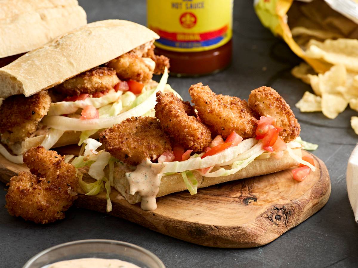 Side view of 7 layer dip with a hand holding a chip scooping some of the dip out.