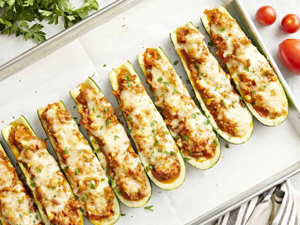 Overhead view of a platter of buffalo wings with ranch sauce in the middle and celery sticks around the sides.