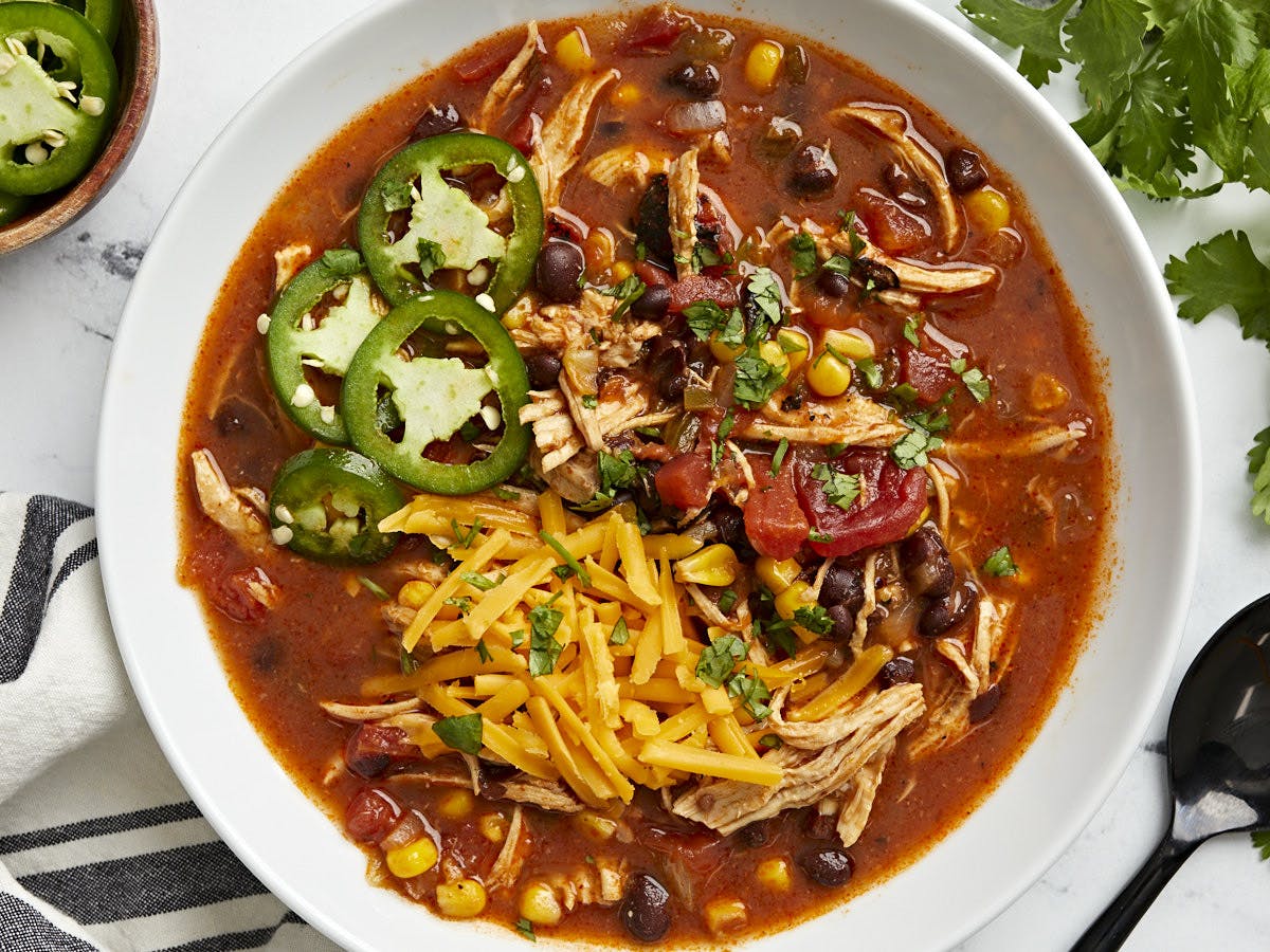 Overhead view of chicken enchilada soup in a white serving bowl.