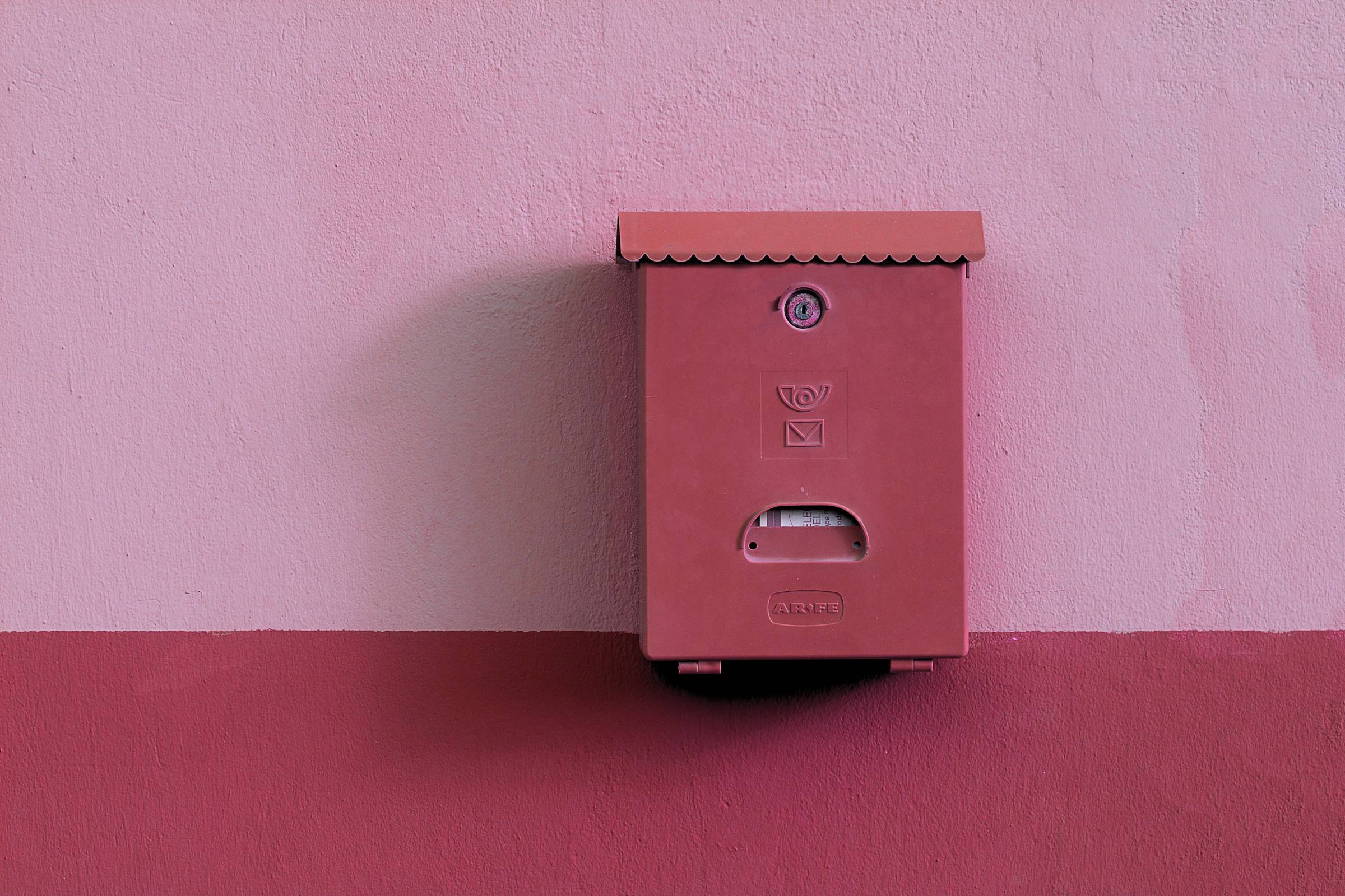 Una cassetta delle poste rosa antico su un muro bicolore rosa e amaranto