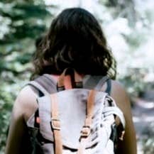 woman in sleeveless top and backpack surrounded by trees during daytime