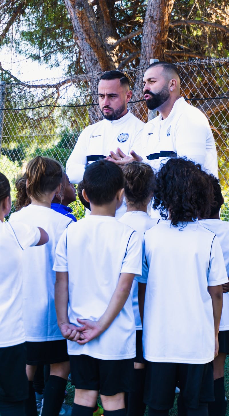 a man in a white uniform talking to a group of children