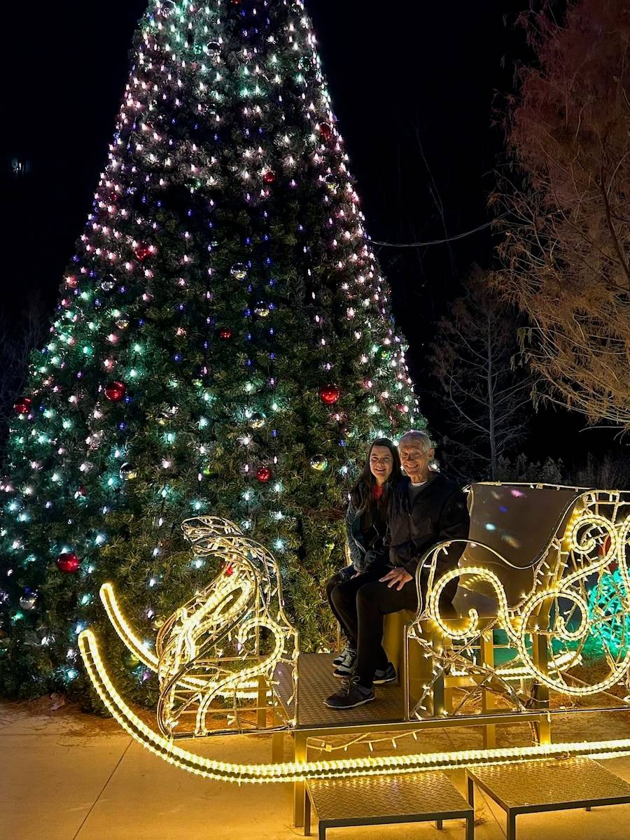 Me and My husband on a sleigh in front of a Christmas Tree