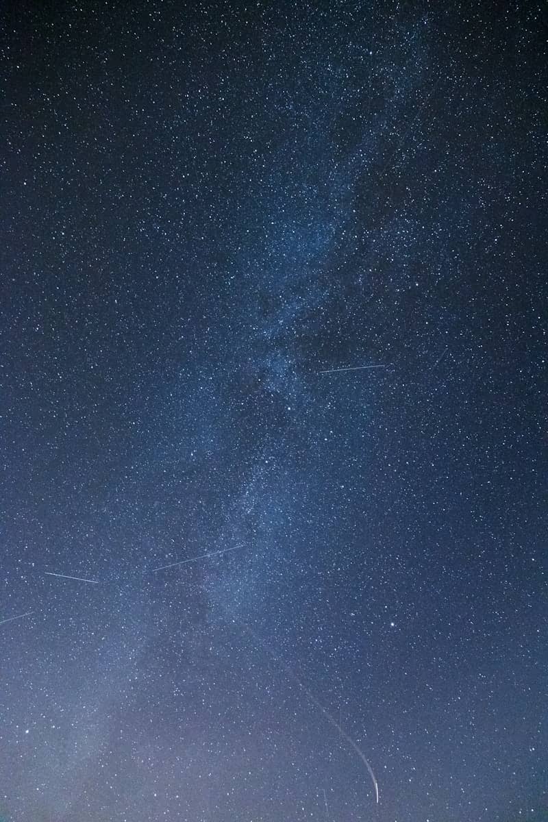 A group of people standing on top of a grass covered field under a night sky