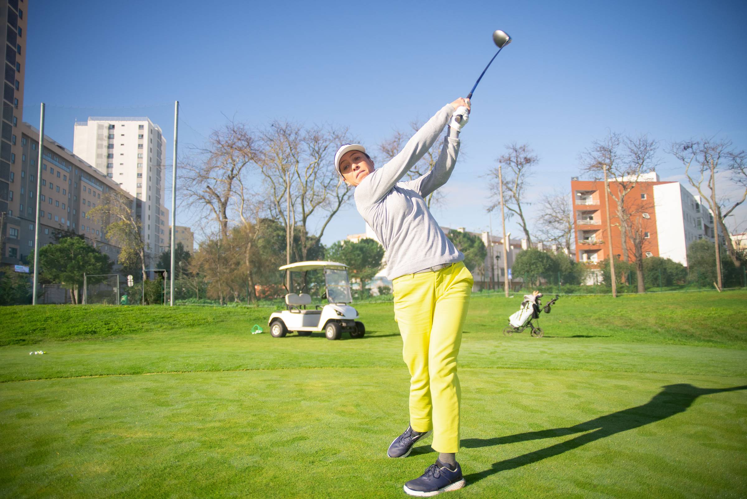 Green golf course with an orange flag and surrounding trees.