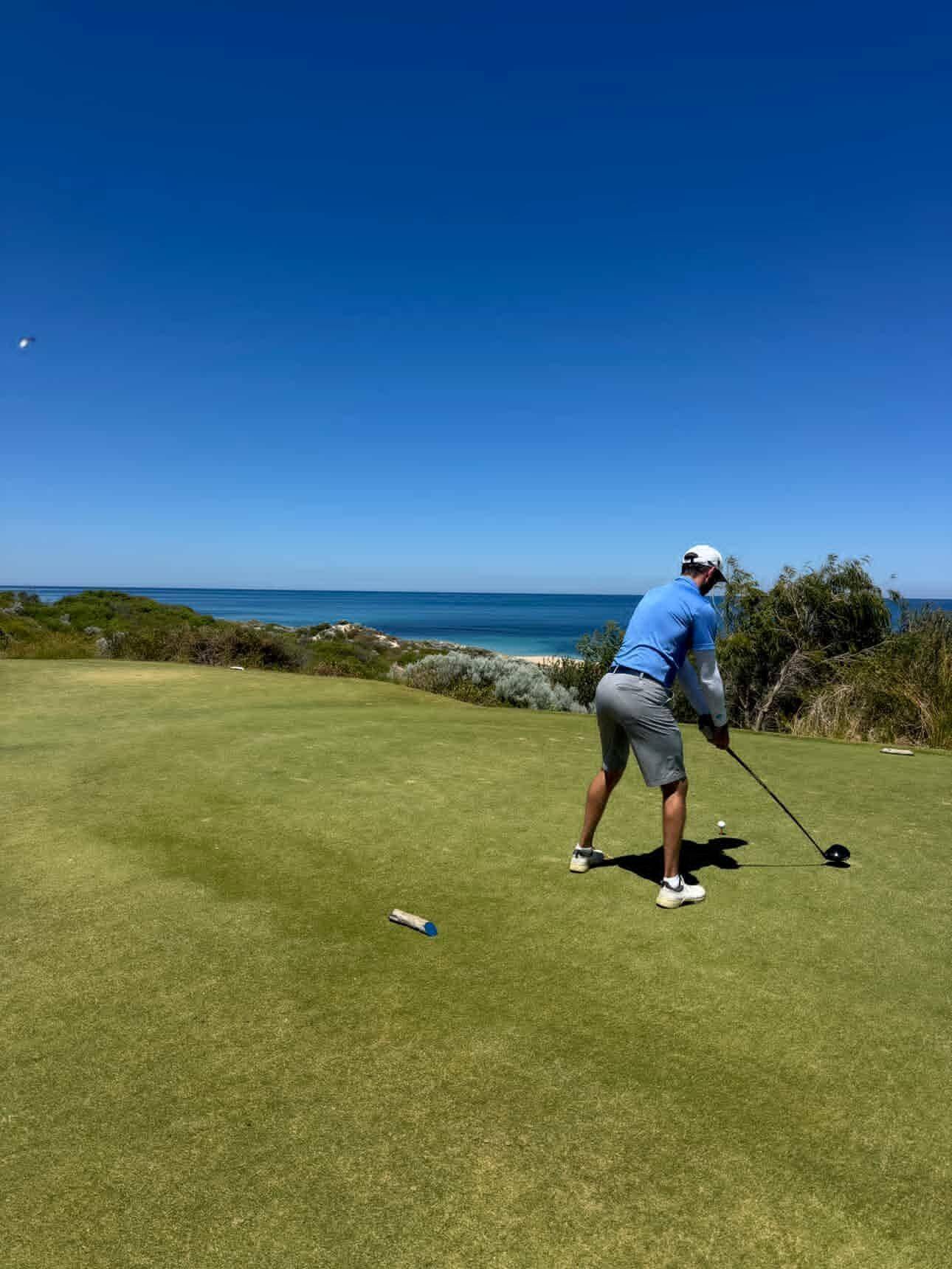A man swings a golf club at a driving range.