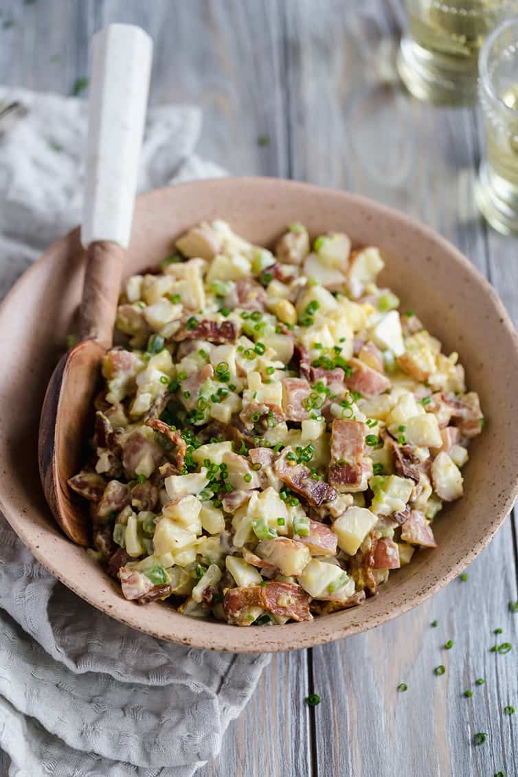 potato salad in a serving bowl with a wood serving spoon