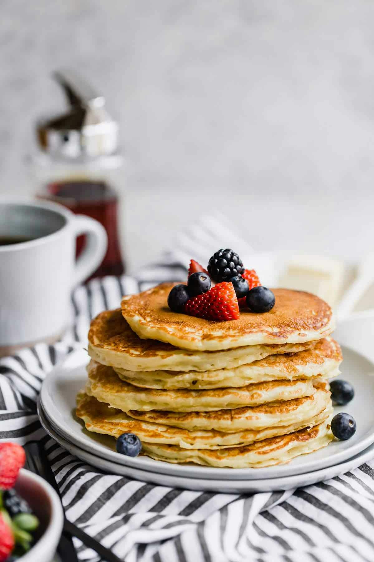 stack of buttermilk pancakes topped with fresh berries on a plate