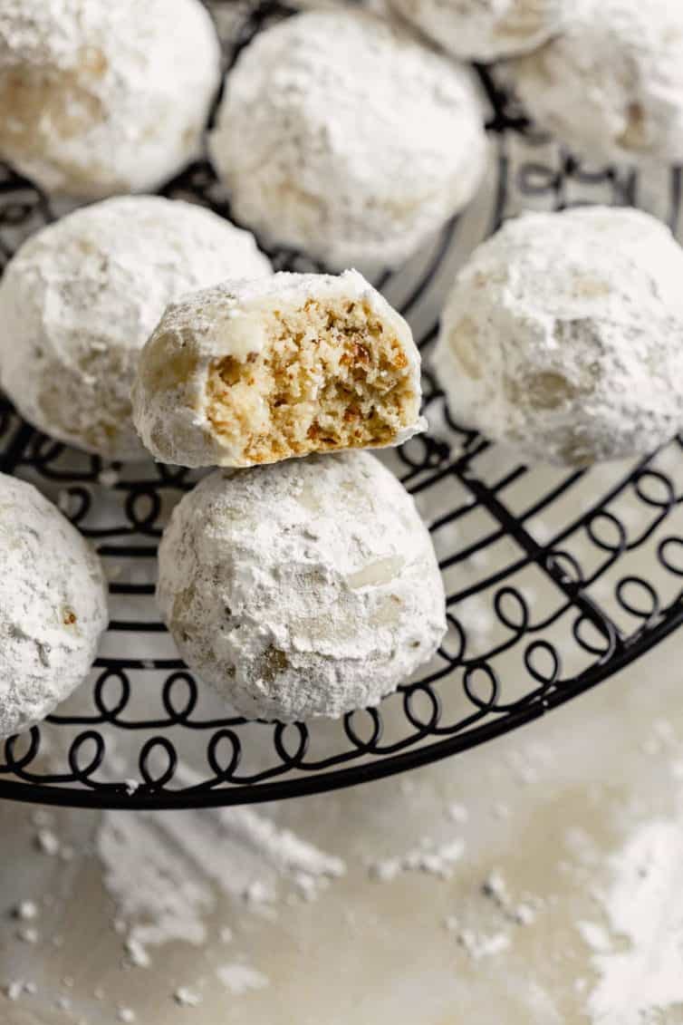 snowball cookies on a cooling rack with a bite taken from one