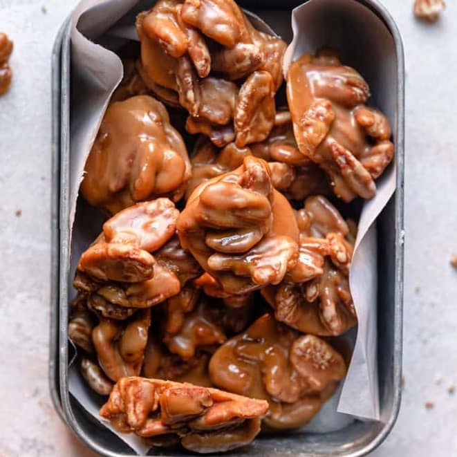 Overhead image of pecan pralines in a parchment paper lined tin.
