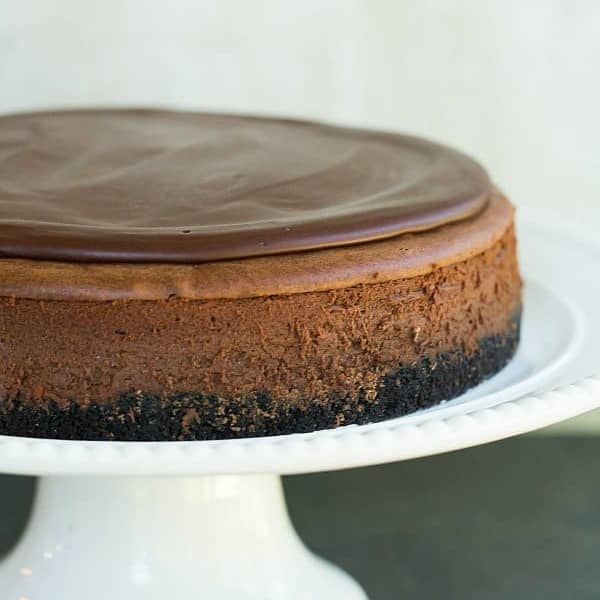 Chocolate cheesecake on a white cake stand.