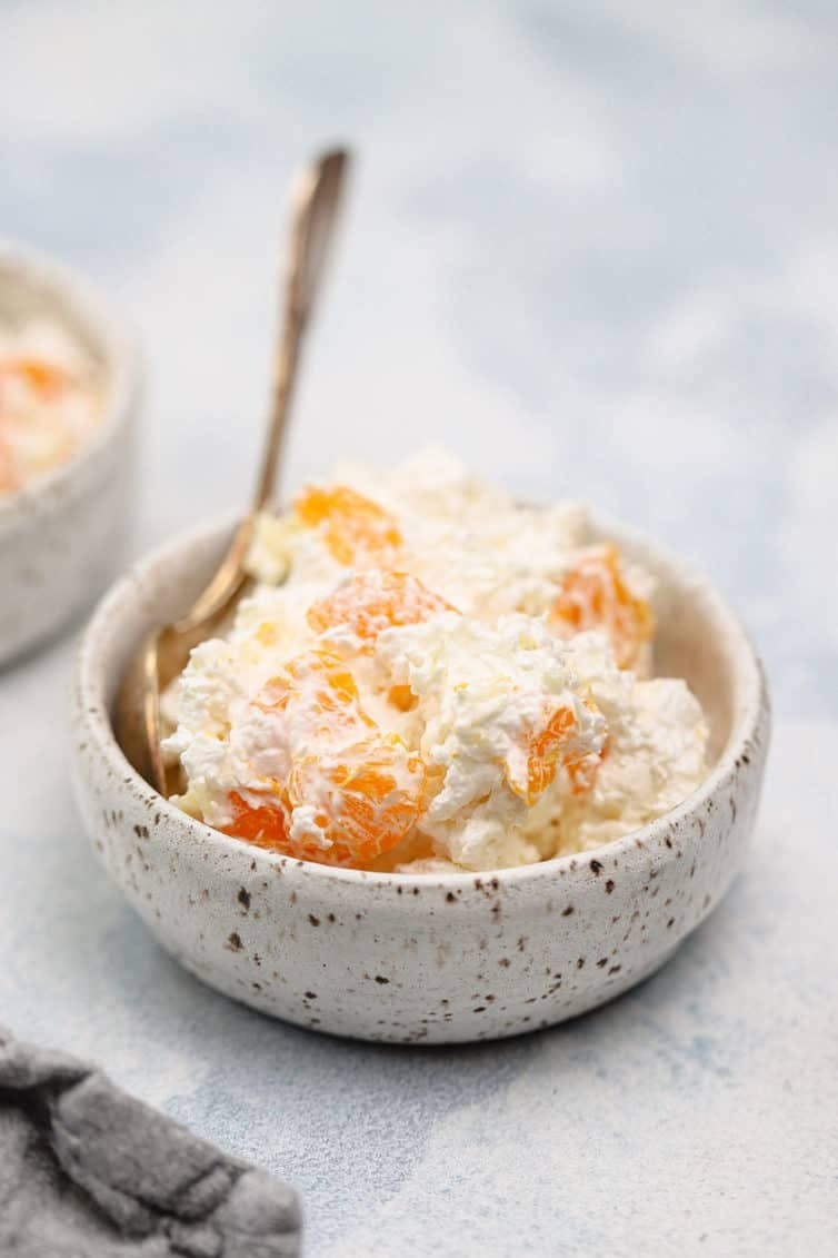 Serving of ambrosia salad in a white bowl with a spoon.