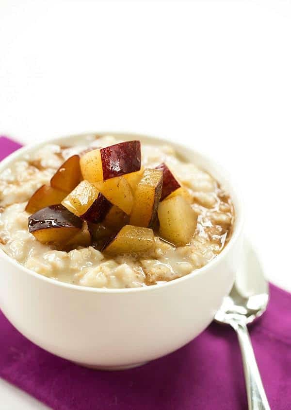 plum oatmeal pudding in a white bowl with a spoon