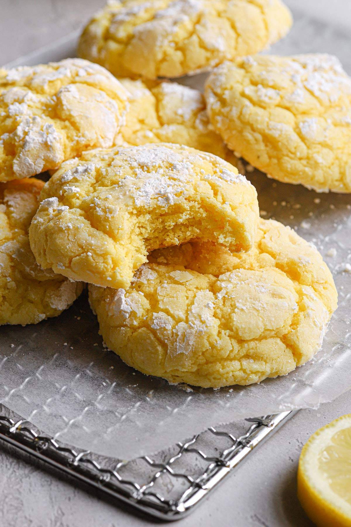 lemon crinkle cookies on a white plate with a bite taken from one