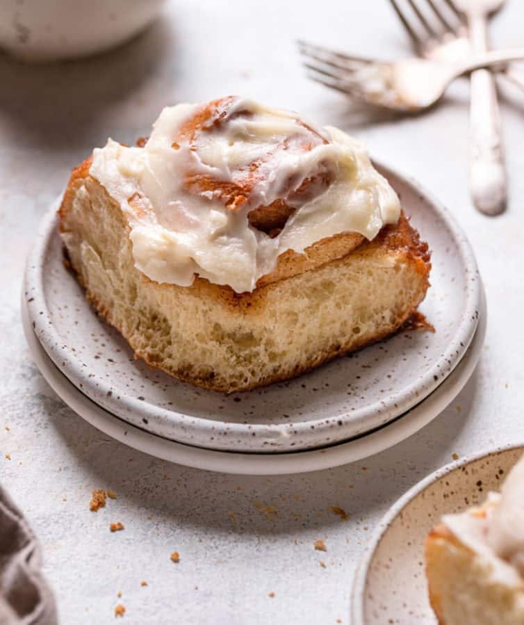 cinnamon roll with cream cheese frosting on a white plate