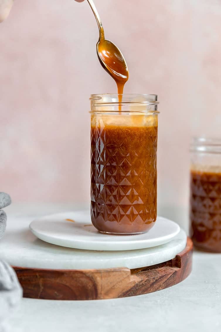 salted caramel sauce in a glass jar with a spoon