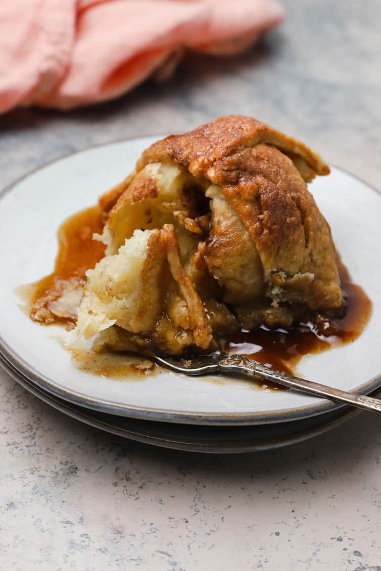 Apple dumpling on a white plate with a fork.