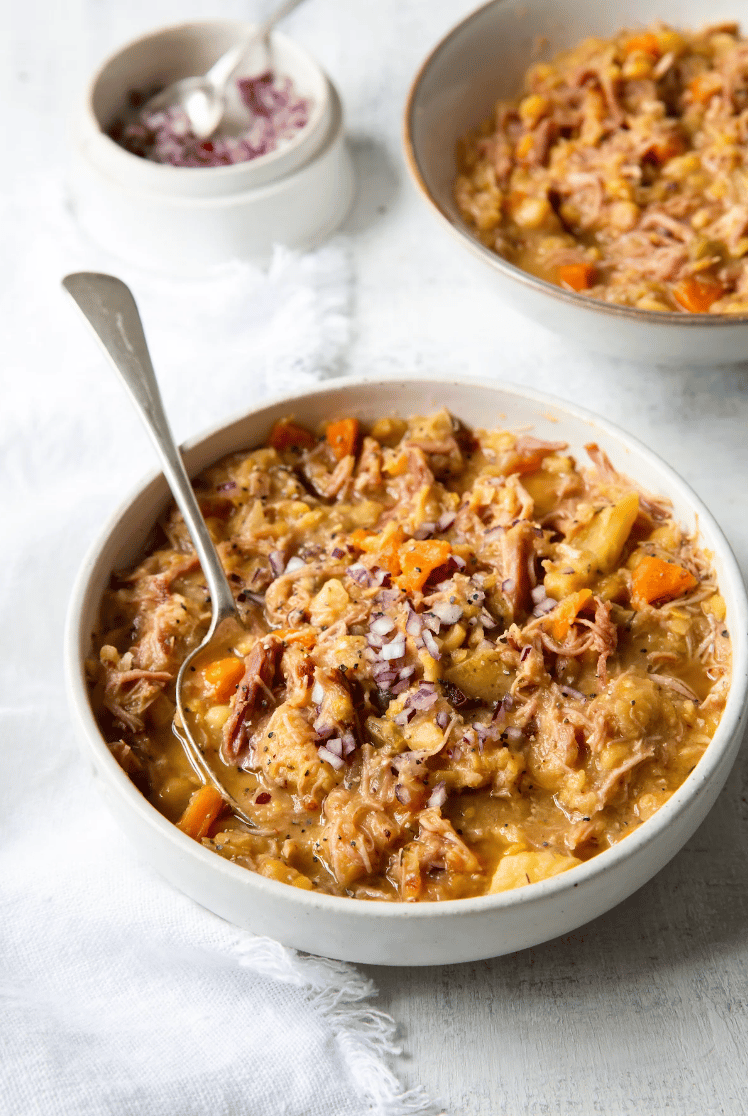 a serving of ham and split pea soup in a white bowl with a spoon