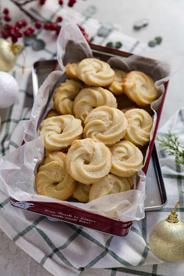 round butter cookies in a parchment paper lined tin