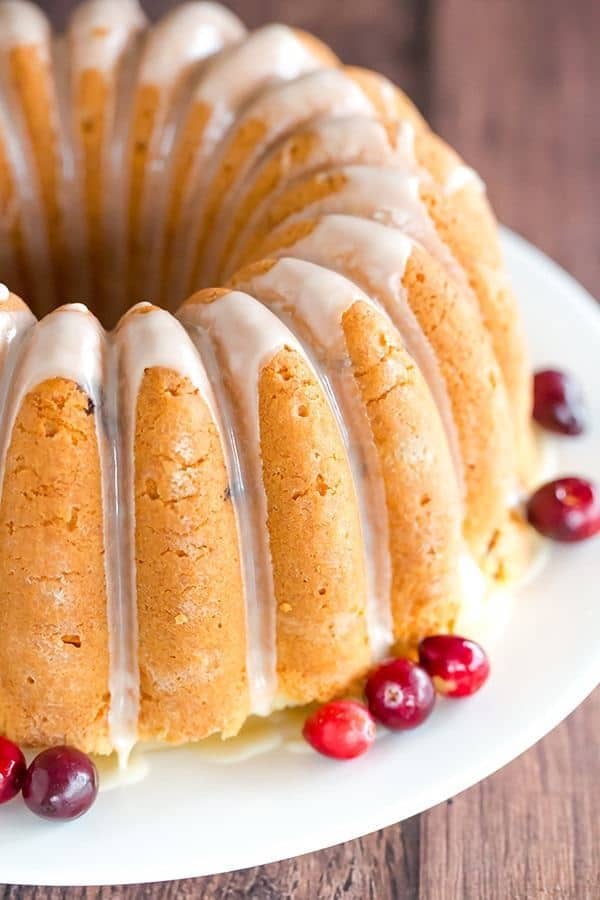 Cranberry orange pound cake with orange glaze on a white plate.