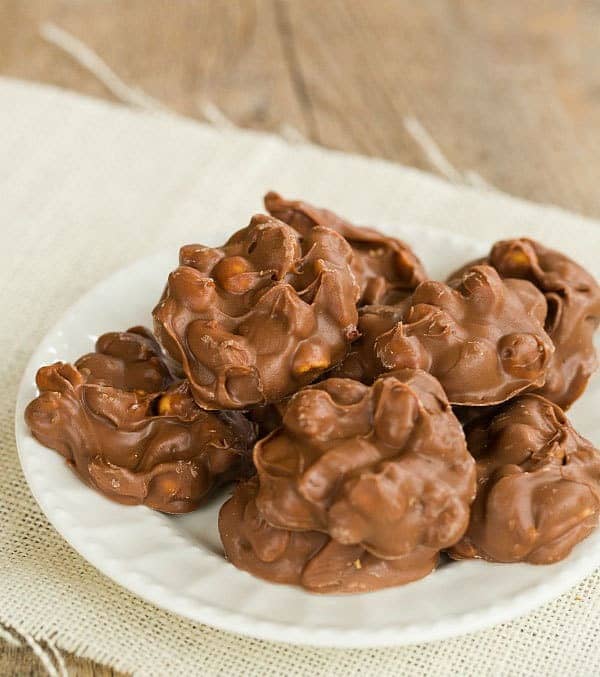 Stack of chocolate peanut clusters on a white plate.