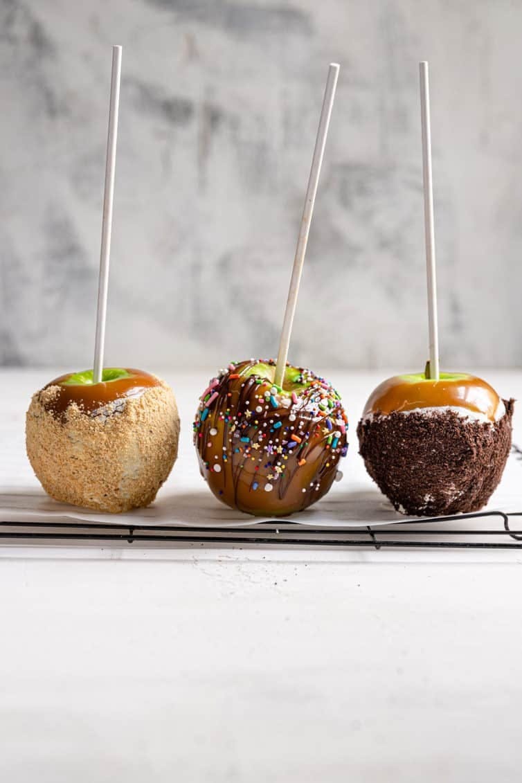 3 caramel apples on a cooling rack.