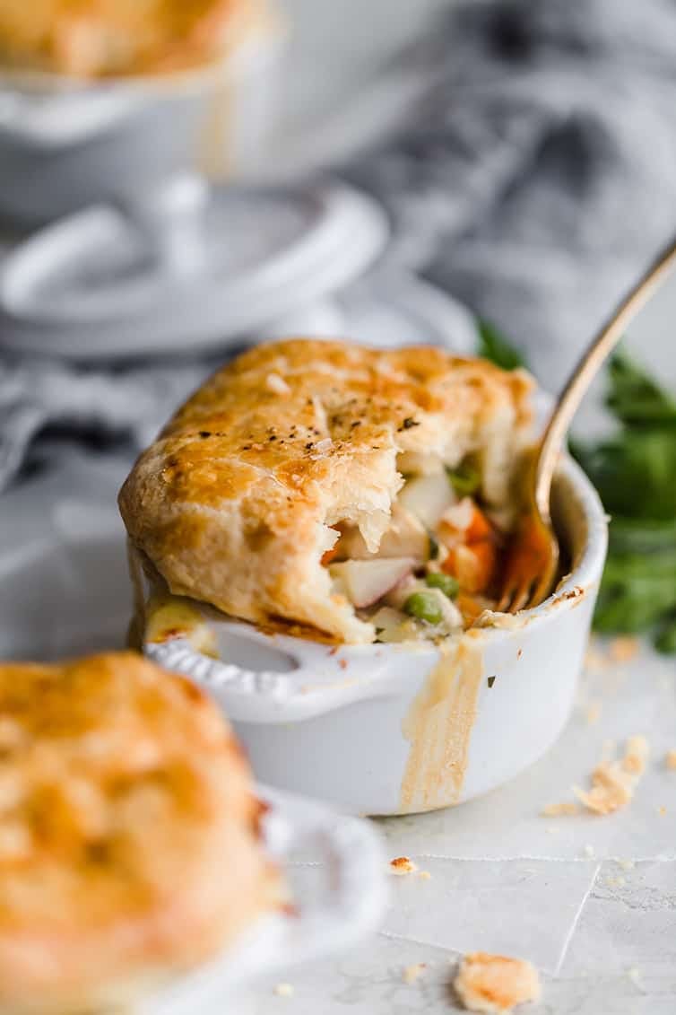 individual serving of chicken pot pie in a white ramekin with a gold fork