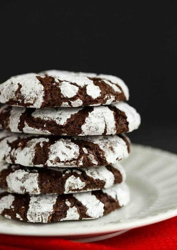 Stack of chocolate crinkle cookies on a white plate.