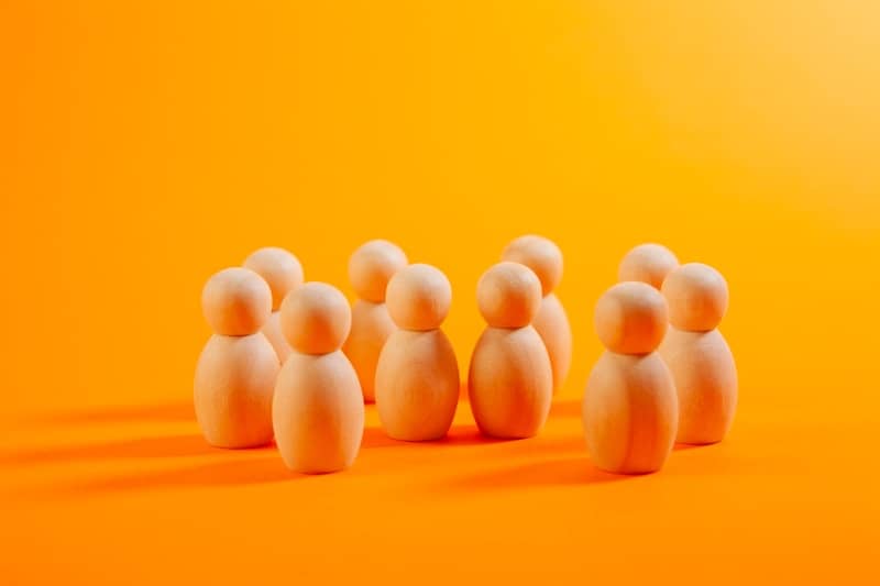 Group of wooden peg people on orange background
