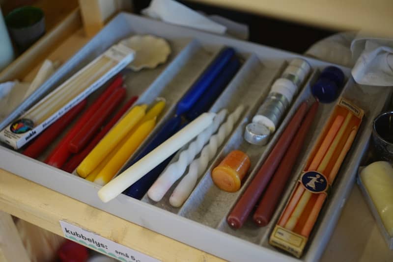 Colorful candles of different shapes arranged in a storage tray.