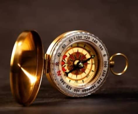 A vintage brass compass rests on a dark surface.