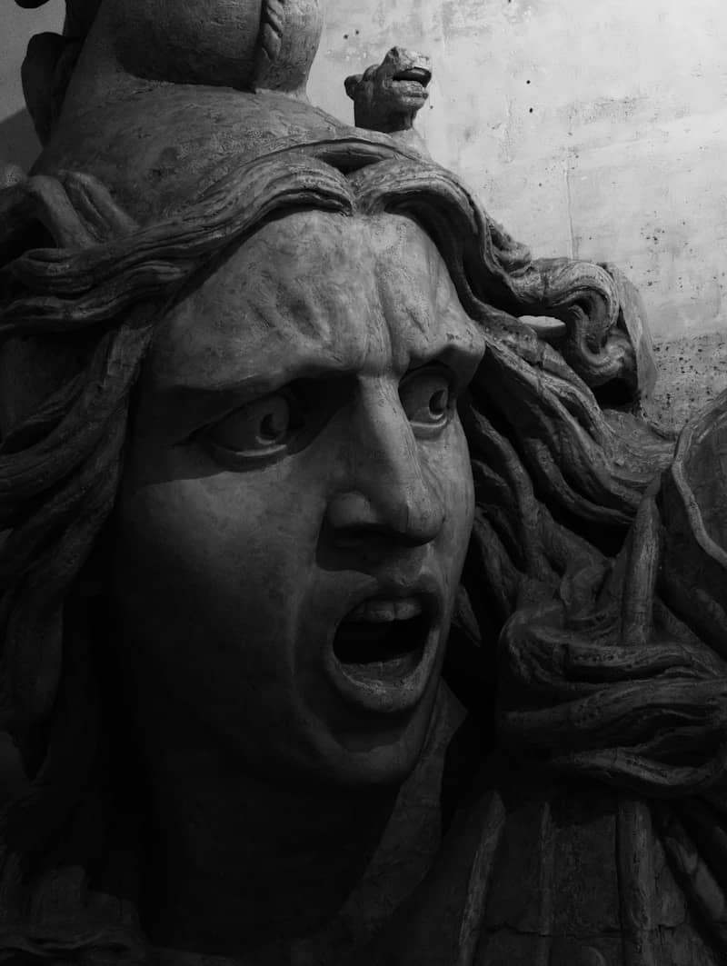 Close-up of a distressed stone sculpture with open mouth.