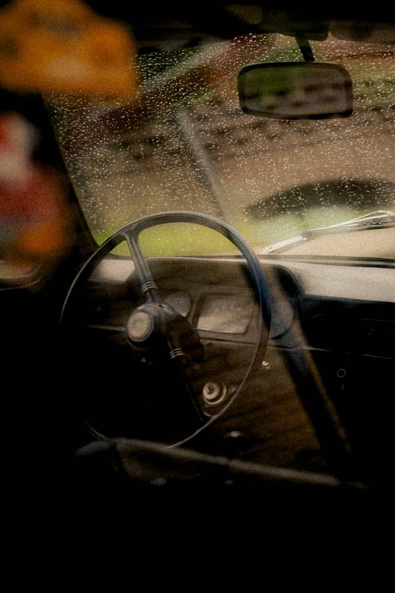 The interior of a vintage car with raindrops on the windshield