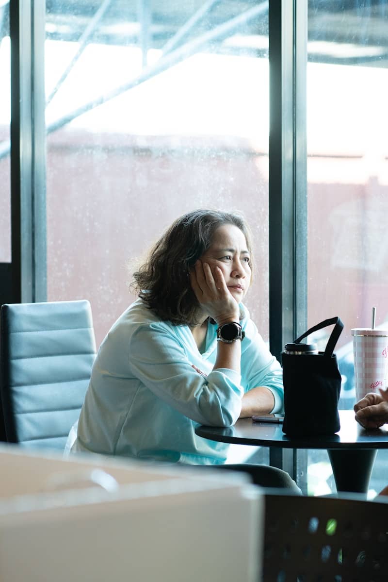 Woman sitting at a table with hand on chin