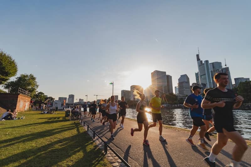 A group of people running down a street next to a river