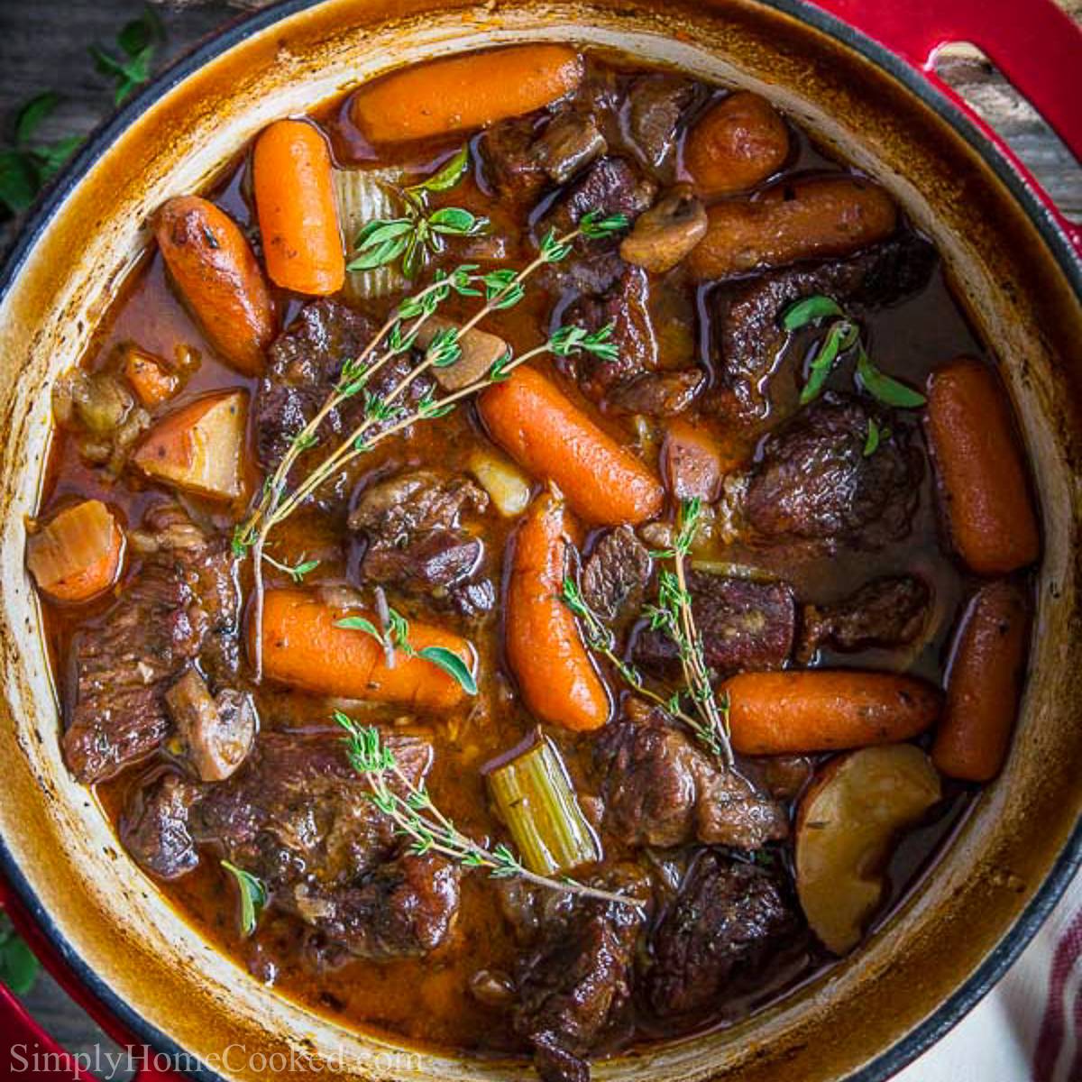 overhead image of beef stew in a red dutch oven pot